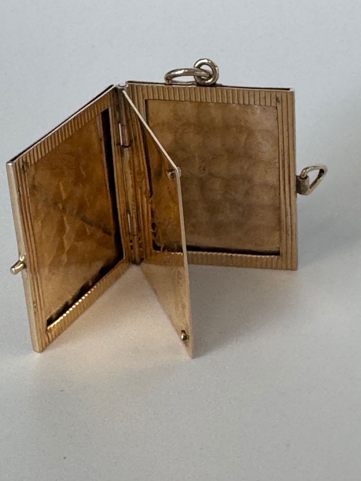 Vintage 14K gold book locket with hinged pages, engine-turned texture, engraved details, multiple photo compartments