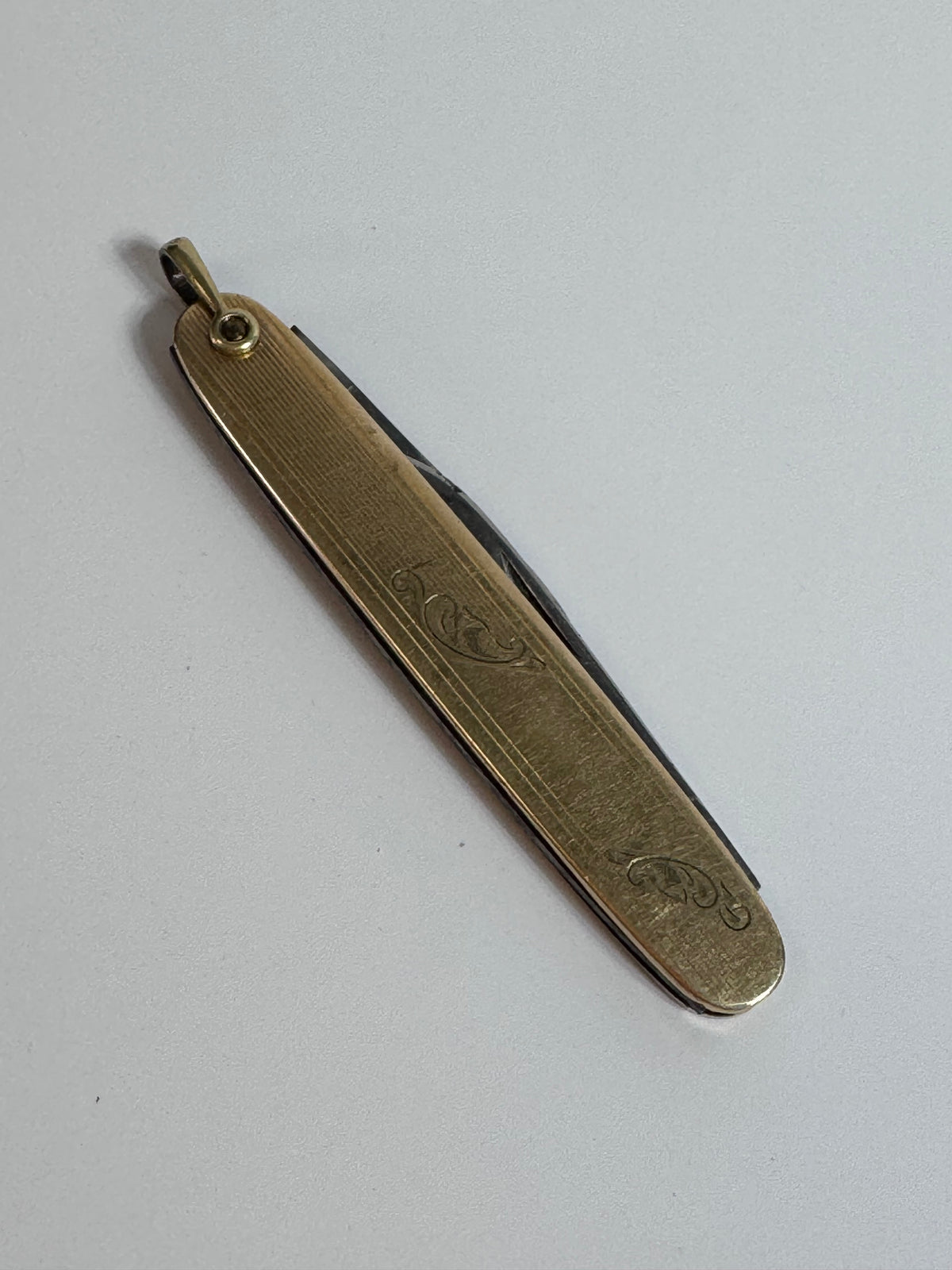 Vintage 10K gold pocket knife pendant with working steel blade, engine turned texture and engraved details, functional jewelry