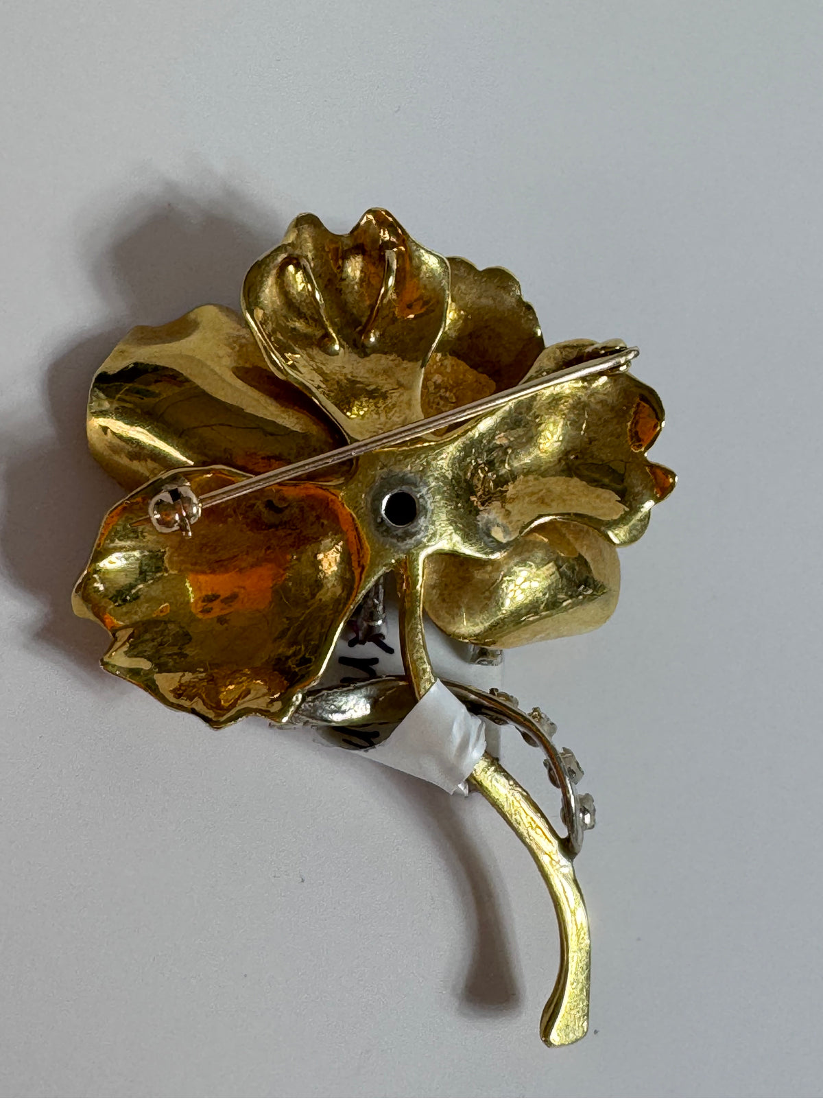 Gold flower-shaped brooch on a light gray background