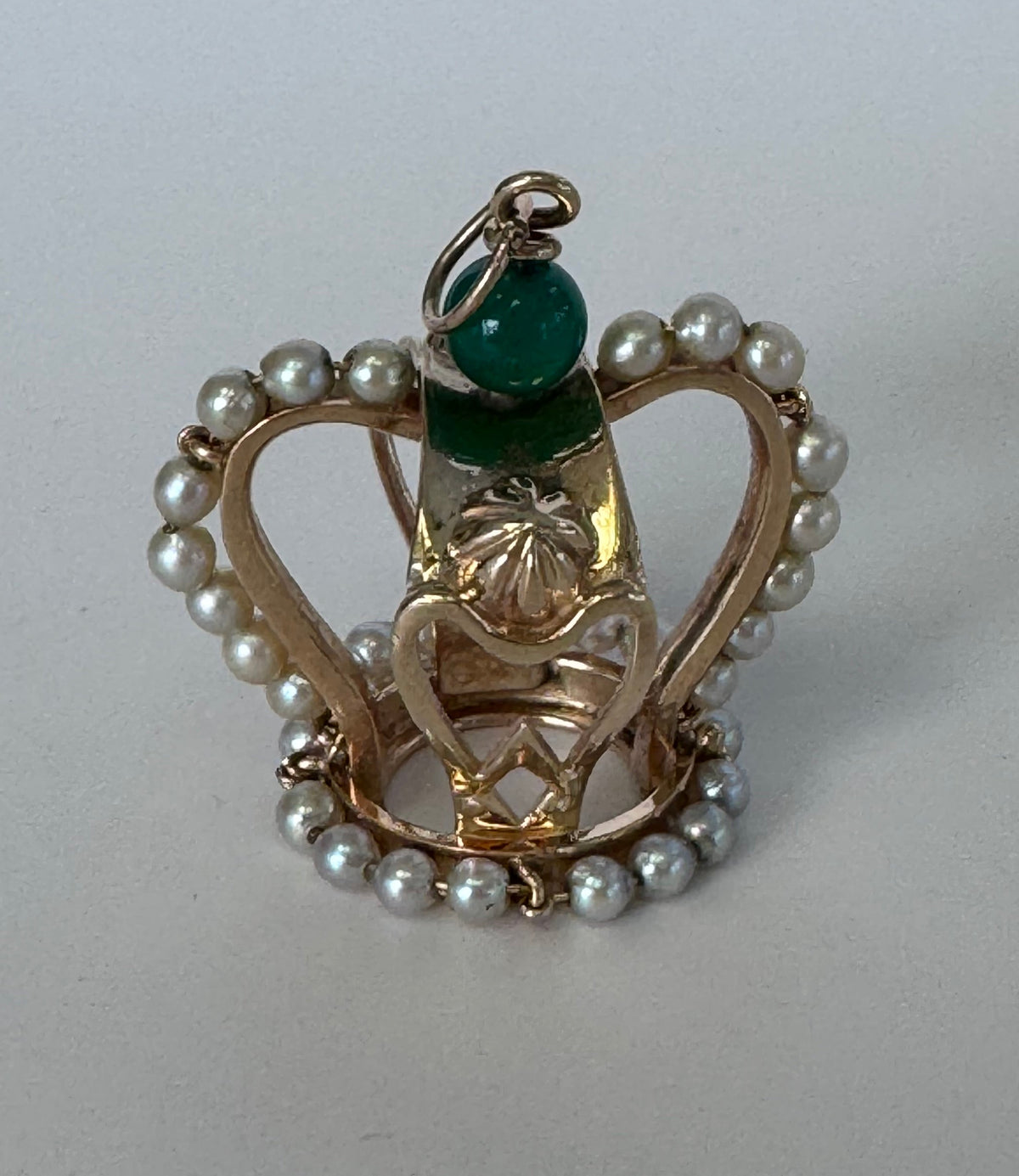 Jewelry item with pearls and a green gemstone on a white background