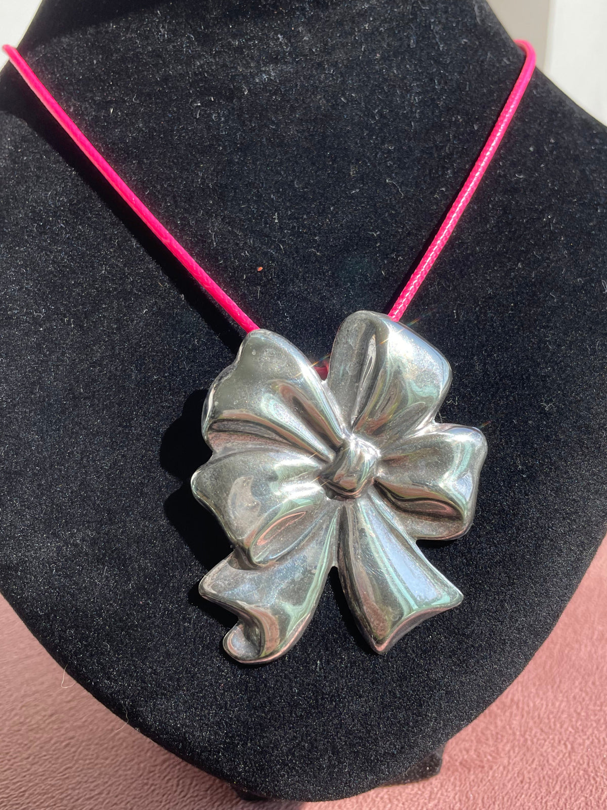 Large estate Mexican sterling silver puffy bow brooch pin pendant with mirror finish, displayed on pink cord necklace